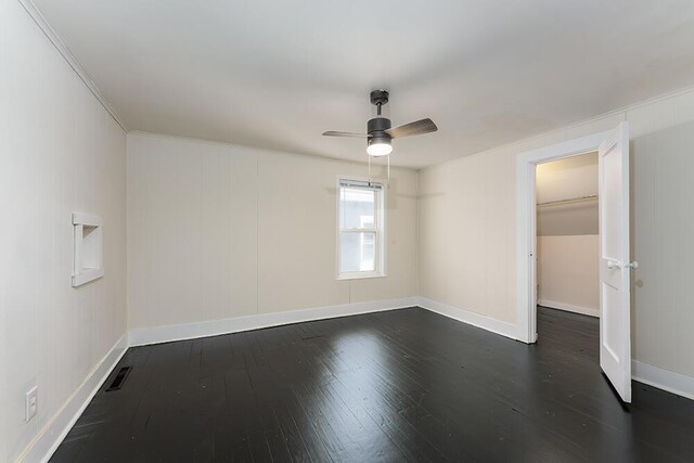 empty room with dark wood-style flooring, attic access, and baseboards