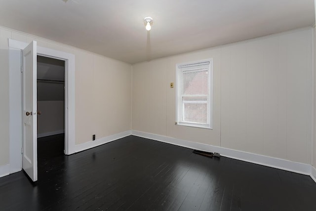 spare room featuring baseboards and dark wood-style flooring