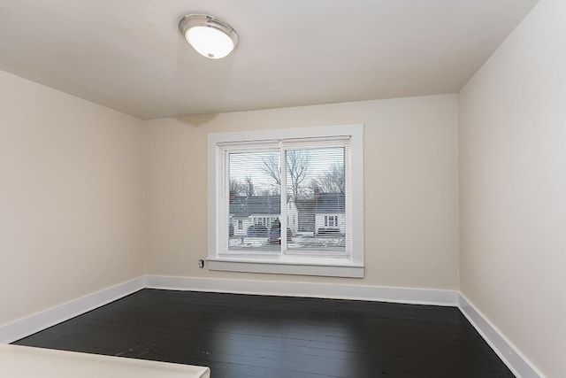 unfurnished room with dark wood-type flooring and baseboards