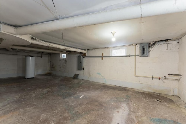 basement with electric panel, a healthy amount of sunlight, and water heater