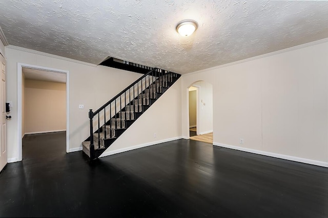 interior space with arched walkways, crown molding, a textured ceiling, baseboards, and stairs