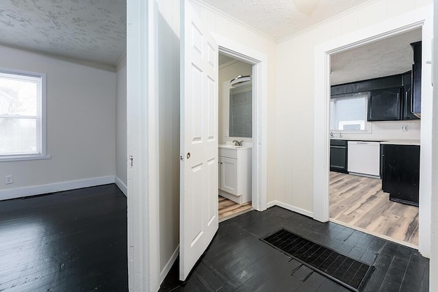 hallway with a sink, baseboards, dark wood finished floors, and a textured ceiling