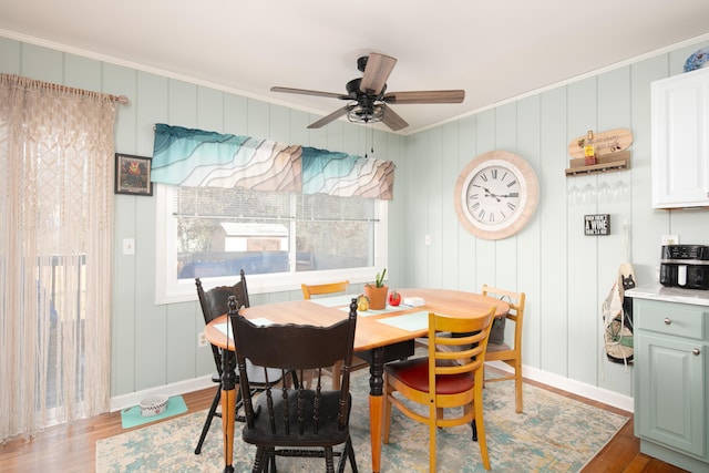 dining room featuring baseboards, ceiling fan, wood finished floors, and crown molding