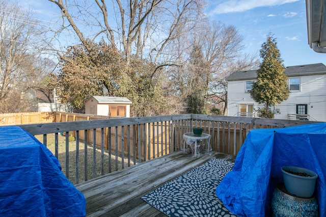 wooden deck with an outbuilding, fence, and a storage shed