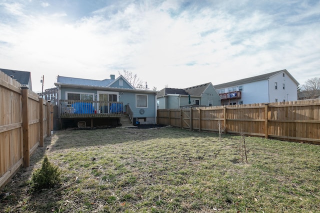 rear view of house featuring a yard, a fenced backyard, and a wooden deck