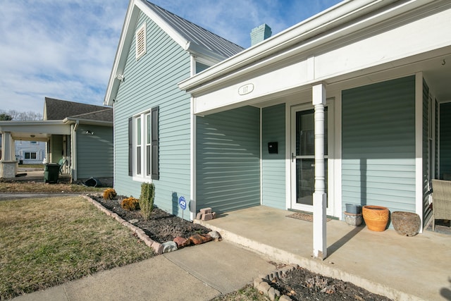 view of exterior entry featuring a chimney and a porch