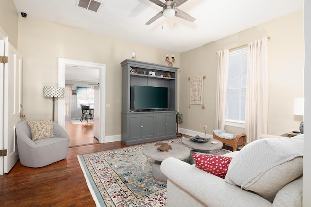 living room with ceiling fan, dark wood finished floors, visible vents, and baseboards