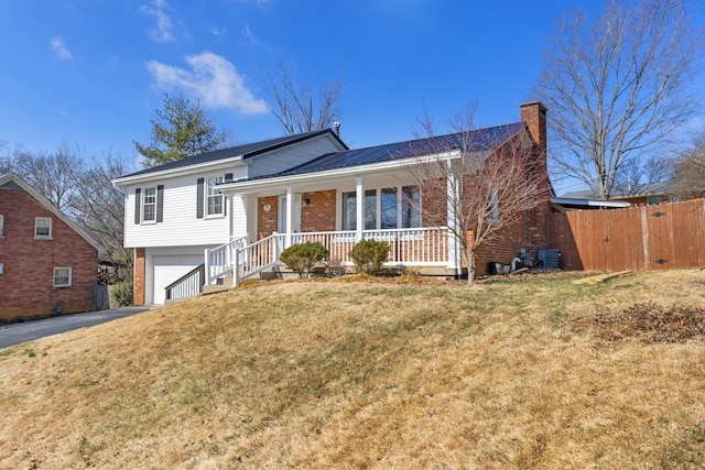 tri-level home with a porch, brick siding, driveway, and central AC