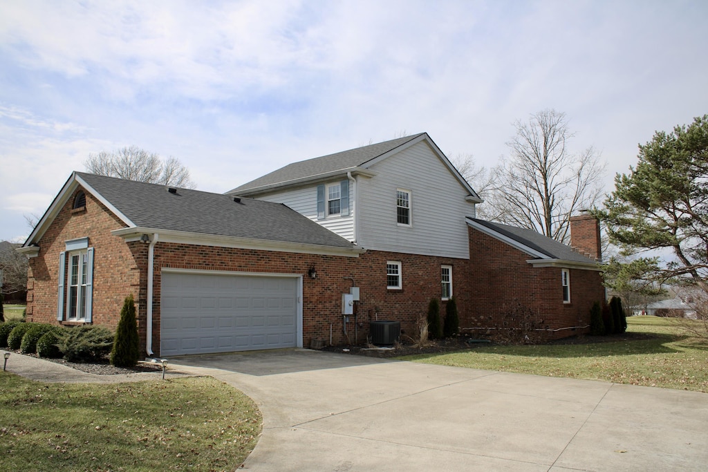 view of home's exterior featuring a garage, brick siding, central AC, and driveway