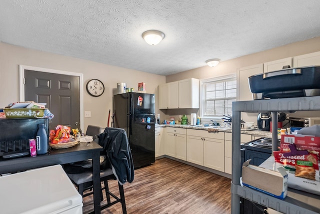 kitchen featuring light countertops, freestanding refrigerator, white cabinetry, a textured ceiling, and wood finished floors