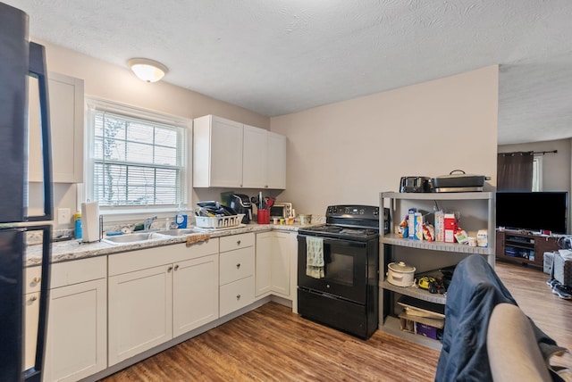 kitchen featuring black appliances, white cabinetry, a sink, and wood finished floors