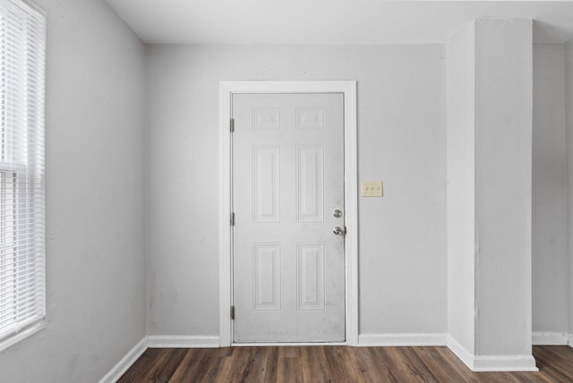 spare room with baseboards and dark wood-style flooring