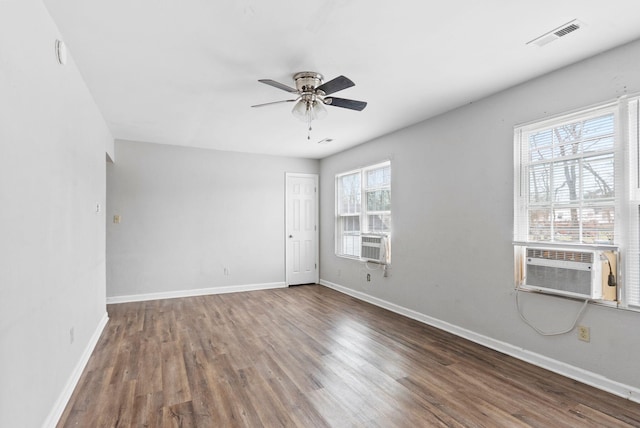 empty room with baseboards, visible vents, a ceiling fan, wood finished floors, and cooling unit