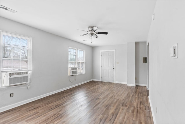 empty room with visible vents, a ceiling fan, wood finished floors, cooling unit, and baseboards