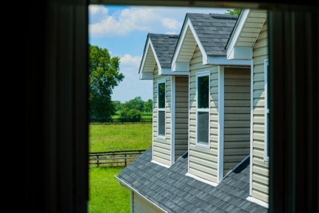 exterior space featuring an outbuilding, roof with shingles, and a lawn