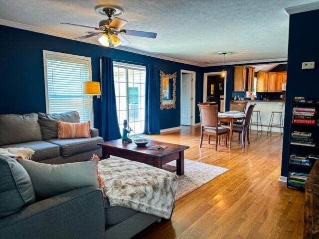 living room with crown molding, a textured ceiling, and light wood finished floors