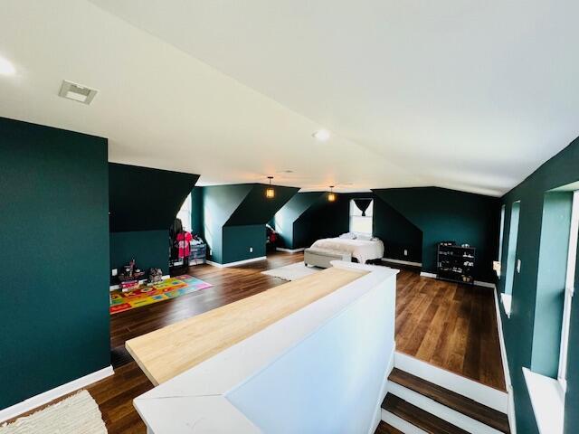 recreation room featuring vaulted ceiling, dark wood-style flooring, visible vents, and baseboards