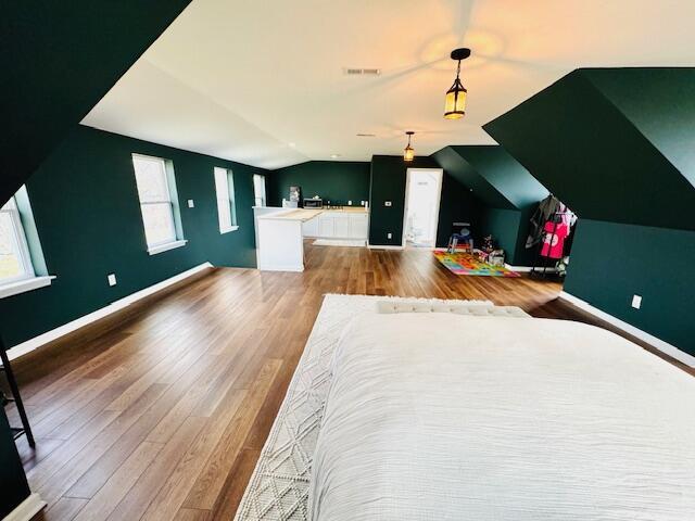 unfurnished bedroom with vaulted ceiling, wood finished floors, visible vents, and baseboards