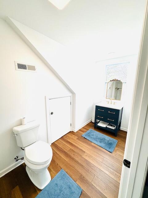 bathroom with visible vents, toilet, vanity, wood finished floors, and baseboards