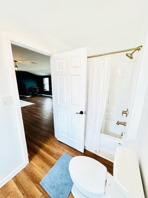 full bathroom featuring shower / tub combo, baseboards, toilet, and wood finished floors