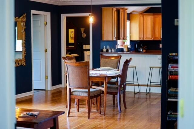 dining room with baseboards, light wood finished floors, and crown molding