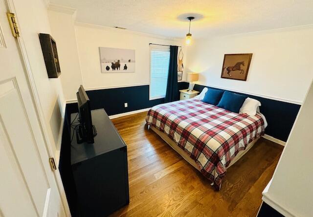 bedroom with baseboards, ornamental molding, and wood finished floors