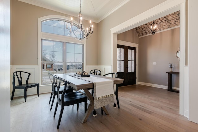 dining space with a healthy amount of sunlight, an inviting chandelier, light wood-style flooring, and french doors