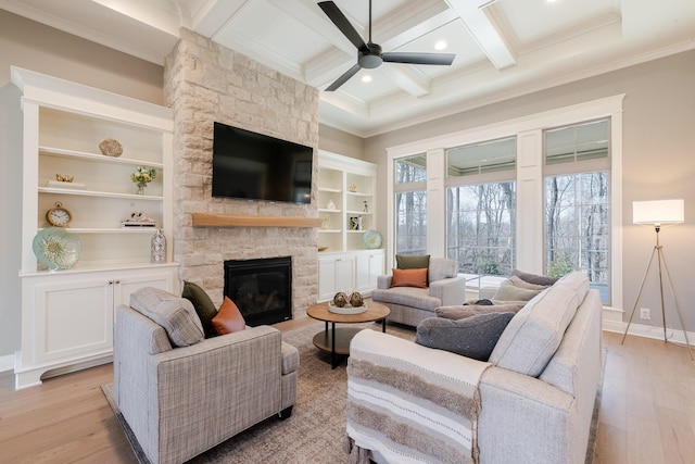 living room featuring beam ceiling, coffered ceiling, light wood-style flooring, and a stone fireplace