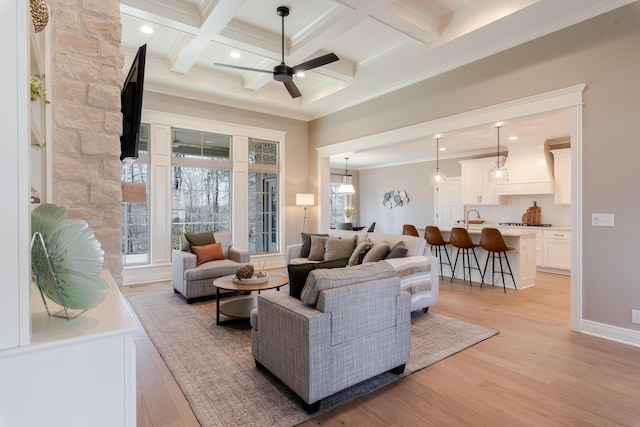 living room with light wood-style flooring, coffered ceiling, a ceiling fan, ornamental molding, and beamed ceiling