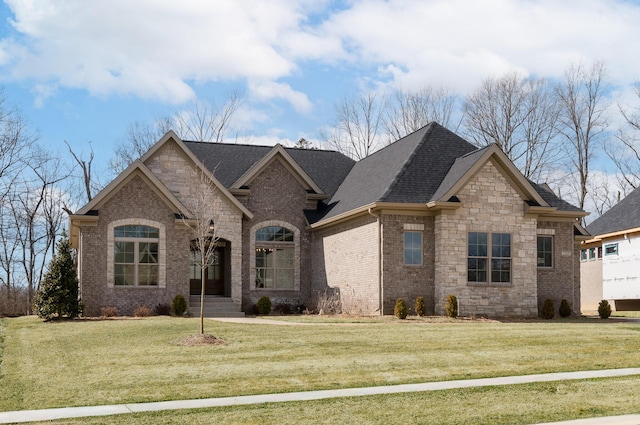 view of front of home with a shingled roof, brick siding, and a front lawn