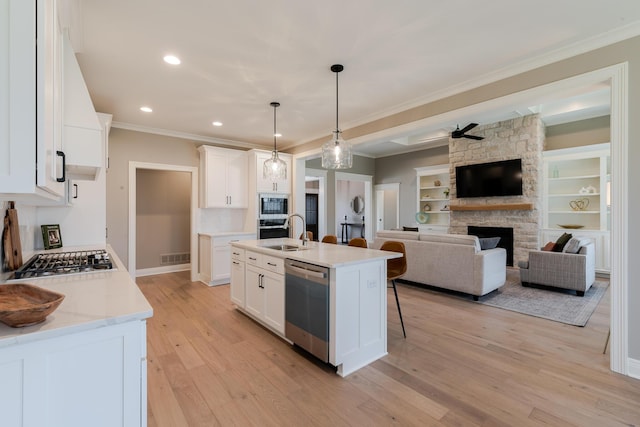 kitchen with a fireplace, a kitchen breakfast bar, open floor plan, appliances with stainless steel finishes, and light wood finished floors