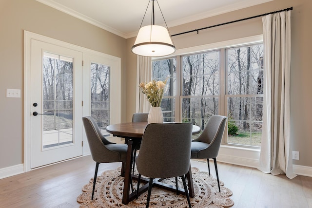 dining room with baseboards, crown molding, and light wood finished floors