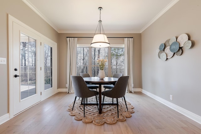 dining space with light wood-type flooring, baseboards, and crown molding