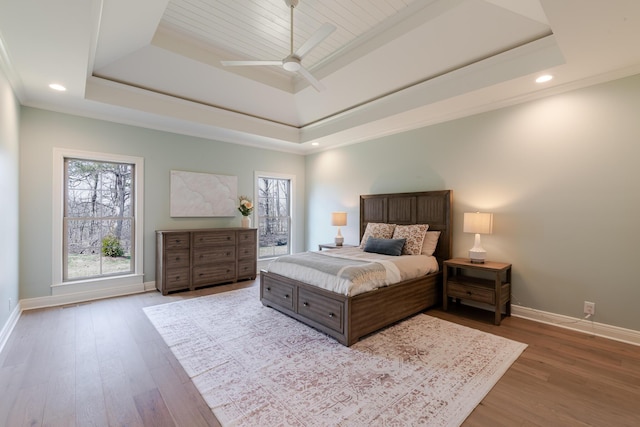 bedroom with crown molding, baseboards, a raised ceiling, and wood finished floors