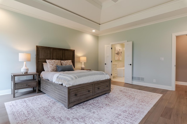 bedroom featuring baseboards, visible vents, wood finished floors, and ensuite bathroom