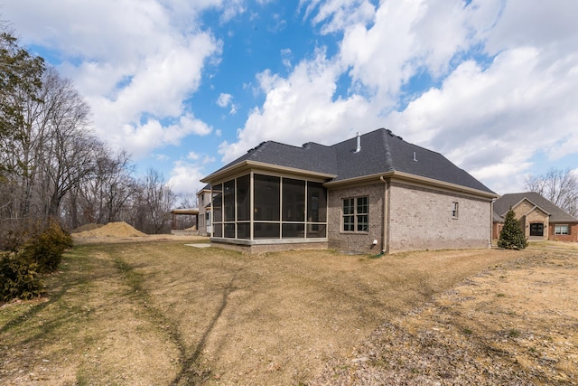 back of house featuring brick siding and a sunroom