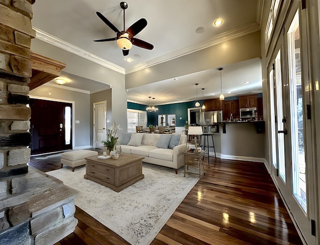 living area featuring baseboards, dark wood-style floors, ornamental molding, ceiling fan with notable chandelier, and recessed lighting