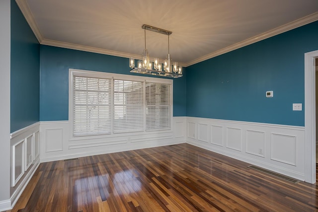 spare room featuring a notable chandelier, visible vents, ornamental molding, wainscoting, and dark wood-style floors