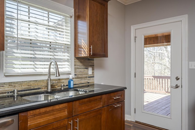 kitchen featuring stainless steel dishwasher, backsplash, a sink, and brown cabinets