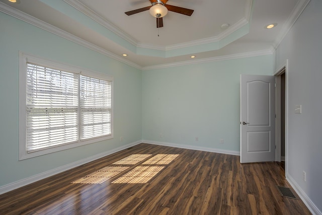 spare room with baseboards, visible vents, ornamental molding, dark wood-style flooring, and a tray ceiling