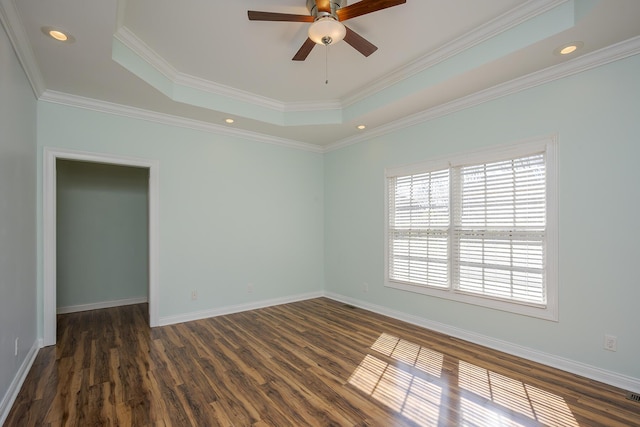 unfurnished room with baseboards, a ceiling fan, dark wood-style floors, a tray ceiling, and crown molding