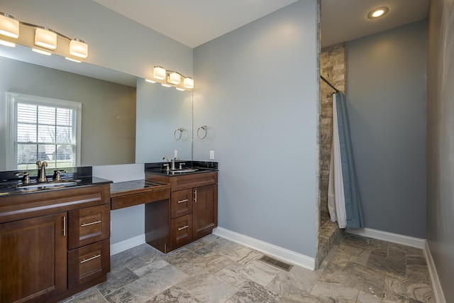 full bath featuring visible vents, tiled shower, vanity, and baseboards