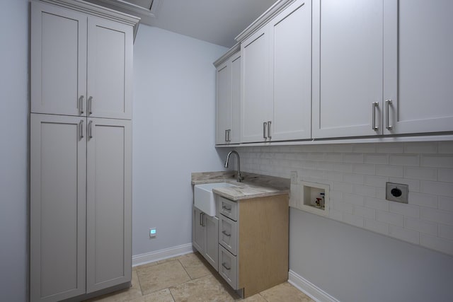 laundry area with hookup for an electric dryer, washer hookup, a sink, baseboards, and cabinet space