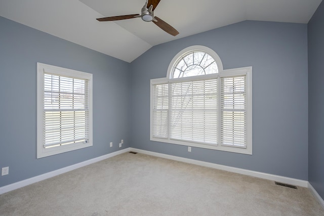 carpeted spare room with lofted ceiling, baseboards, visible vents, and ceiling fan