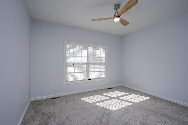 carpeted spare room with ceiling fan, visible vents, and baseboards