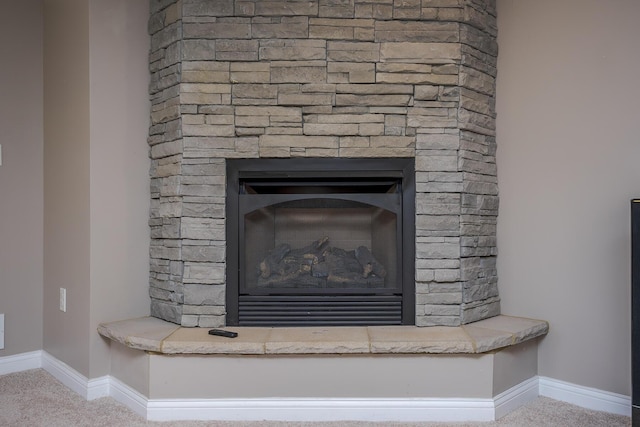 room details with carpet, baseboards, and a stone fireplace