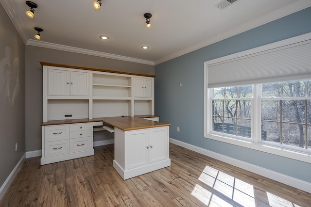 unfurnished office featuring built in study area, crown molding, baseboards, and wood finished floors