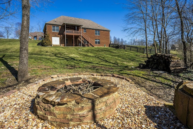 rear view of property with brick siding, a yard, stairway, an outdoor fire pit, and a deck