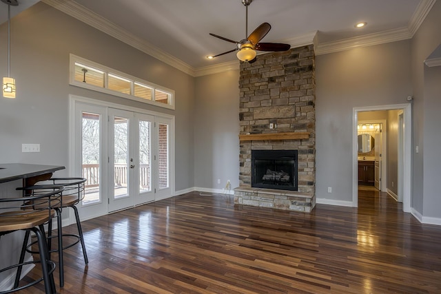 living area featuring baseboards, ornamental molding, wood finished floors, and a stone fireplace