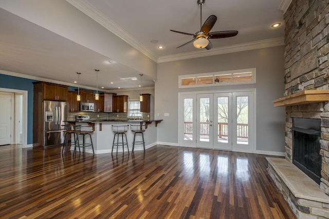 unfurnished living room featuring baseboards, a fireplace, ornamental molding, and dark wood-type flooring